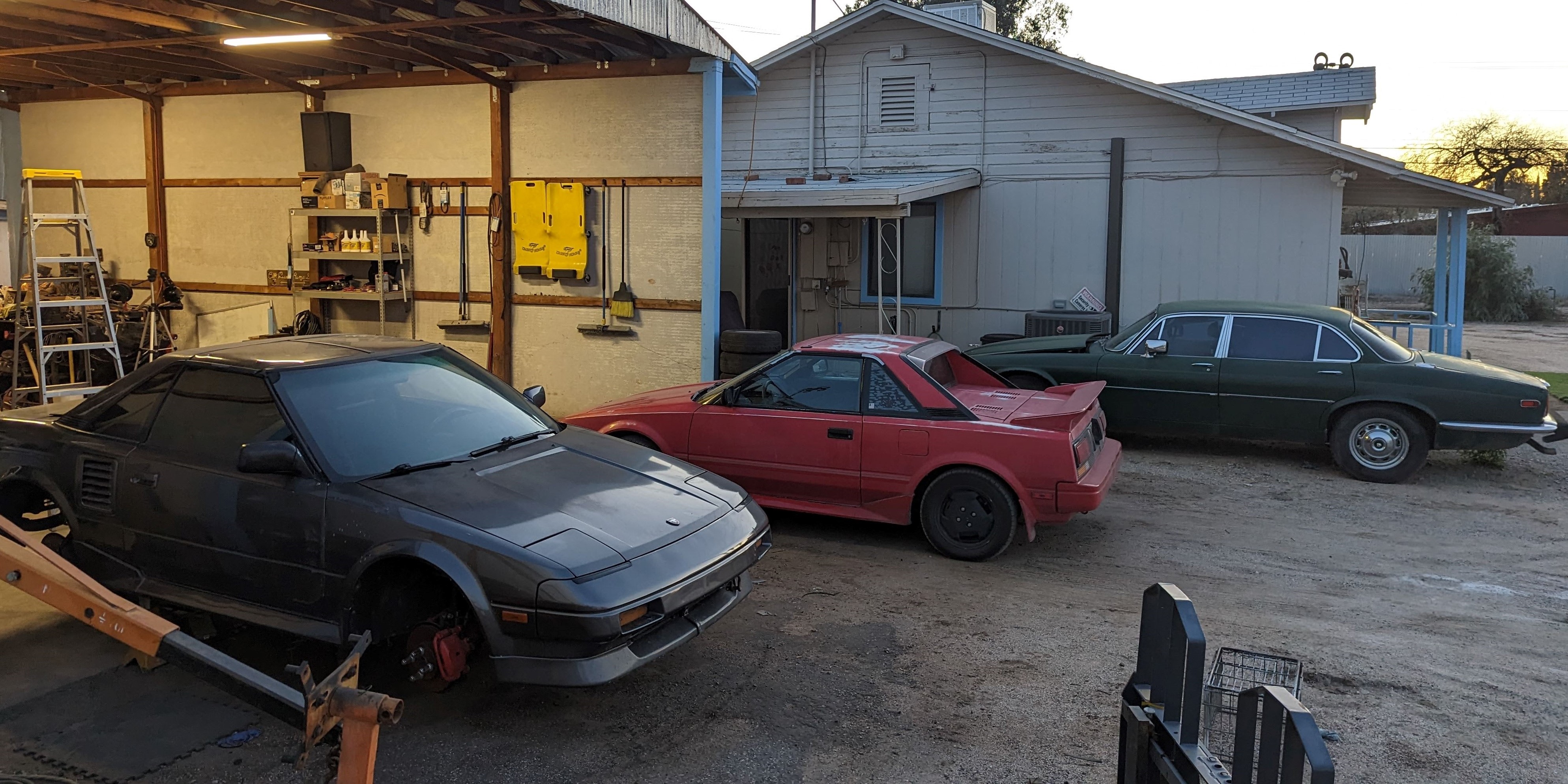 AW11 MR2s and Jaguar XJ in front of shop